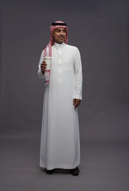 رجل سعودي بالزي التقليدي يحمل كوب قهوة