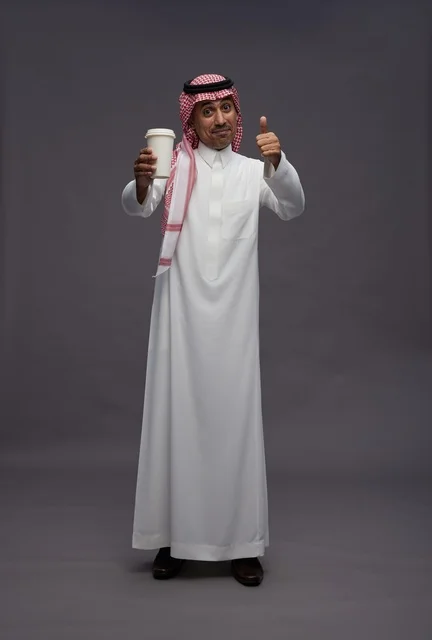 رجل سعودي بالزي التقليدي يحمل كوب قهوة