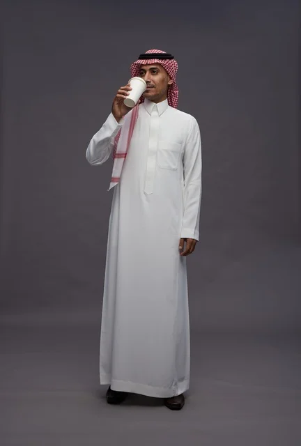 رجل سعودي بالزي التقليدي يشرب القهوة