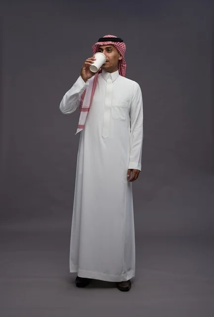 رجل سعودي بالزي التقليدي يشرب القهوة في الاستوديو