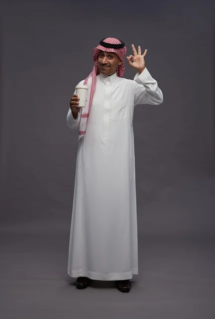 رجل سعودي بالزي التقليدي يحمل كوب قهوة