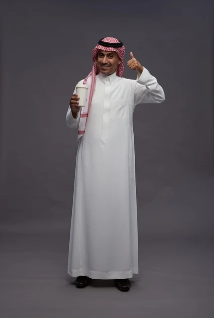 رجل سعودي بالزي التقليدي يحمل كوب قهوة في الاستوديو