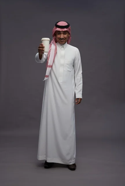 رجل سعودي يرتدي الزي التقليدي ويحمل كوب قهوة ورقي رجل سعودي يرتدي الزي التقليدي ويحمل كوب قهوة ورقي