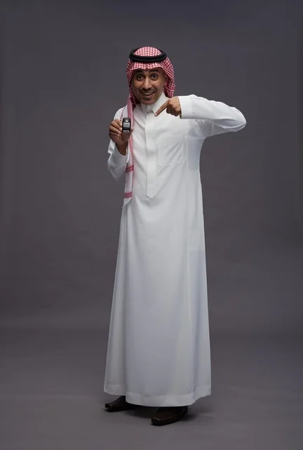 رجل سعودي بالزي التقليدي يحمل مفتاح سيارة