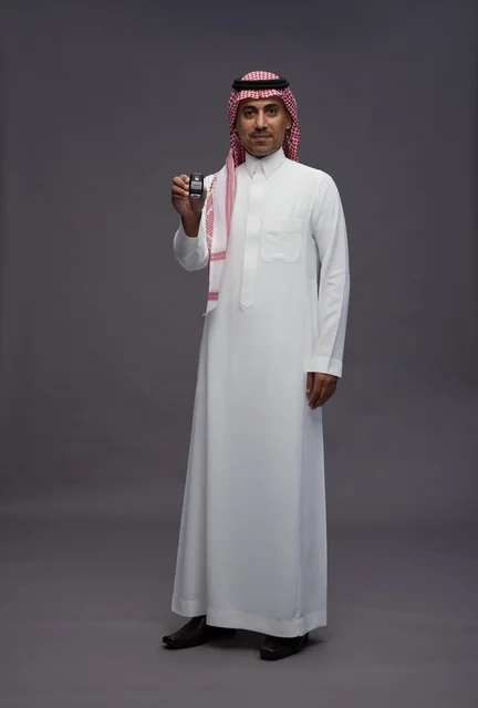 رجل سعودي بالزي التقليدي يحمل مفتاح سيارة في الاستوديو
