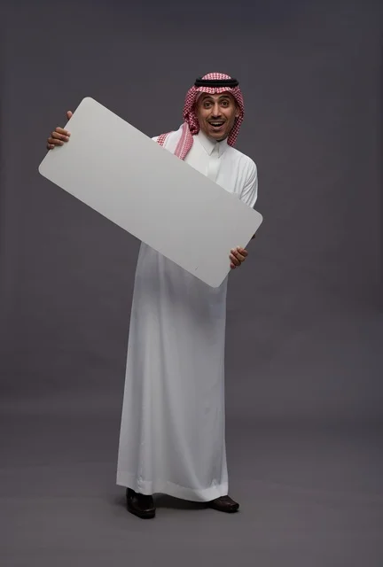 رجل سعودي بالثوب يحمل لوحة بيضاء فارغة للعرض رجل سعودي بالثوب يحمل لوحة بيضاء فارغة للعرض