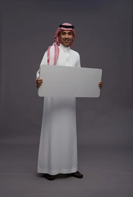 رجل سعودي يحمل لوحة بيضاء فارغة للعرض