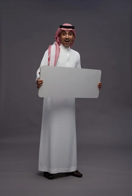 رجل سعودي يحمل لوحة بيضاء فارغة للعرض رجل سعودي يحمل لوحة بيضاء فارغة للعرض