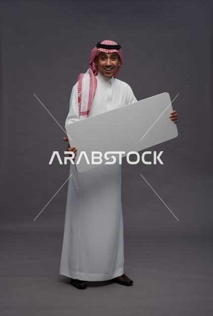 رجل سعودي يمسك لوحة بيضاء فارغة في الاستوديو