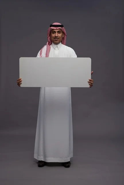 رجل سعودي يحمل لوحة بيضاء فارغة في استوديو رجل سعودي يحمل لوحة بيضاء فارغة في استوديو