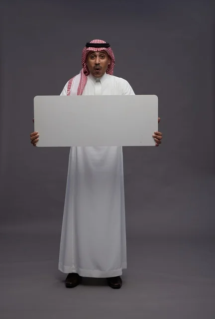 رجل سعودي مندهش يحمل لوحة بيضاء فارغة للعرض
