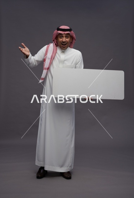 رجل سعودي يحمل لوحة بيضاء فارغة بتعبير مندهش