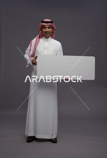 رجل سعودي يحمل لوحة بيضاء فارغة في الاستوديو