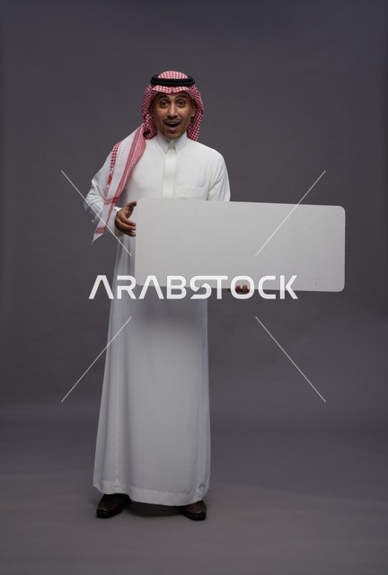رجل سعودي بالزي التقليدي يحمل لوحة بيضاء فارغة للعرض
