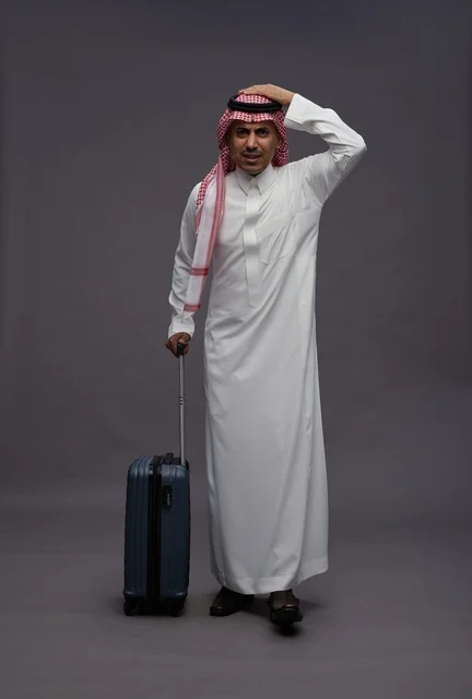 رجل سعودي بالزي التقليدي يحمل حقيبة سفر بتعبير قلق