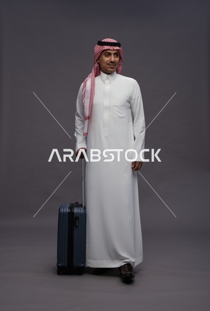 رجل سعودي يحمل حقيبة سفر بالزي التقليدي