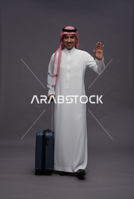رجل سعودي بالزي التقليدي يحمل حقيبة سفر ويلوح