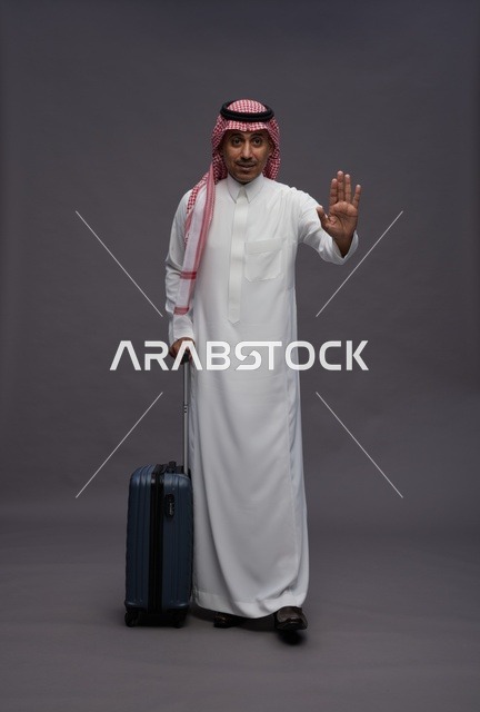 رجل سعودي مع حقيبة سفر يقوم بإشارة التوقف