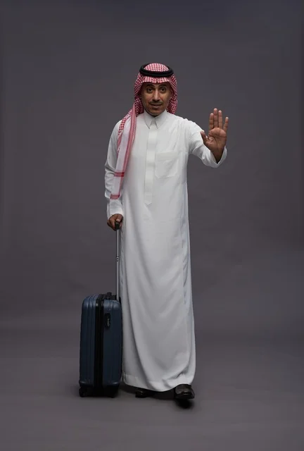 رجل سعودي مع حقيبة سفر يقوم بإشارة التوقف