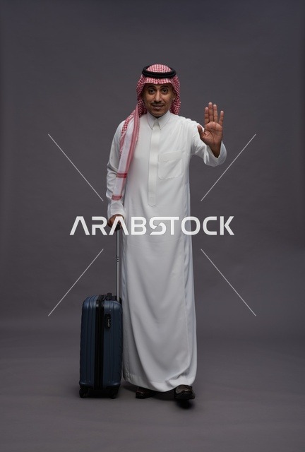 رجل سعودي يحمل حقيبة سفر ويقوم بإشارة التوقف