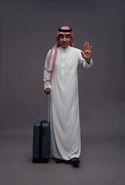 رجل سعودي يحمل حقيبة سفر ويقوم بإشارة التوقف