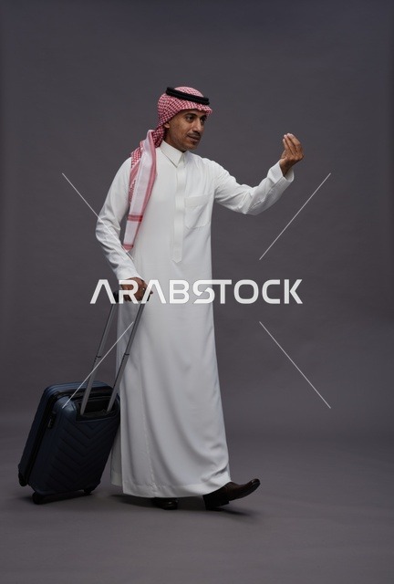 رجل سعودي بالزي التقليدي يحمل حقيبة سفر