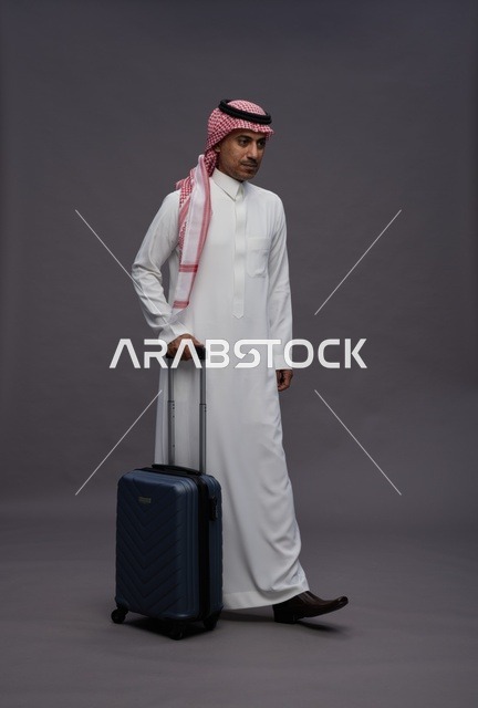 رجل سعودي بالزي التقليدي يحمل حقيبة سفر