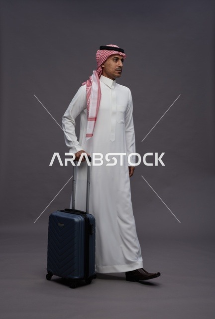 رجل سعودي بالزي التقليدي يحمل حقيبة سفر