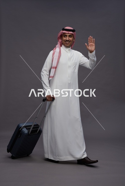 رجل سعودي بالزي التقليدي يحمل حقيبة سفر في الاستوديو