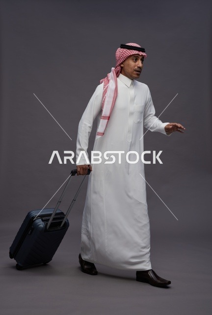 رجل سعودي بالزي التقليدي يمشي مع حقيبة سفر