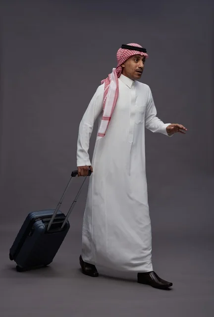 رجل سعودي بالزي التقليدي يمشي مع حقيبة سفر