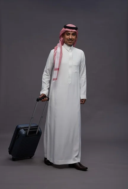 رجل سعودي بالزي التقليدي يحمل حقيبة سفر في استوديو