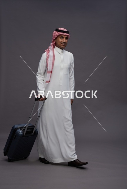 رجل سعودي بالزي التقليدي يحمل حقيبة سفر