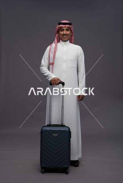 رجل سعودي بالزي التقليدي مع حقيبة سفر في استوديو