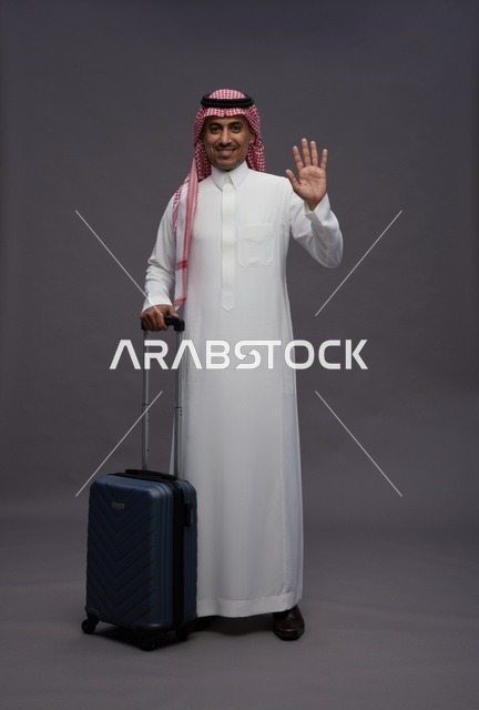 رجل سعودي بالزي التقليدي يحمل حقيبة سفر يلوح بيده