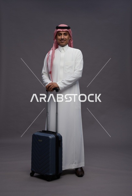رجل سعودي بالزي التقليدي مع حقيبة سفر في الاستوديو