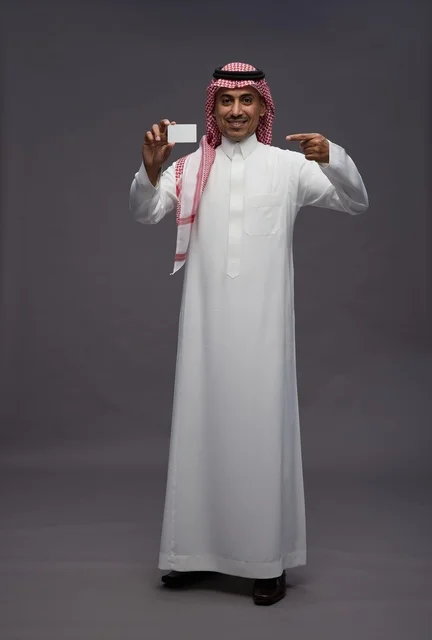 رجل سعودي بالزي التقليدي يحمل بطاقة ائتمان بيضاء رجل سعودي بالزي التقليدي يحمل بطاقة ائتمان بيضاء