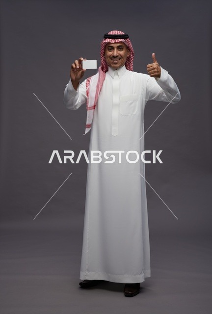 رجل سعودي يحمل بطاقة ائتمان مع إيماءة الإبهام