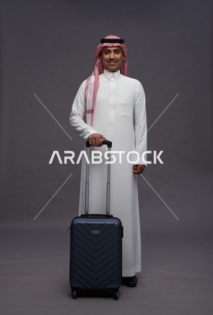 رجل سعودي بالزي التقليدي يحمل حقيبة سفر