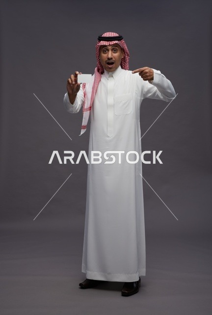رجل سعودي يحمل بطاقة ائتمان بتعبير مندهش