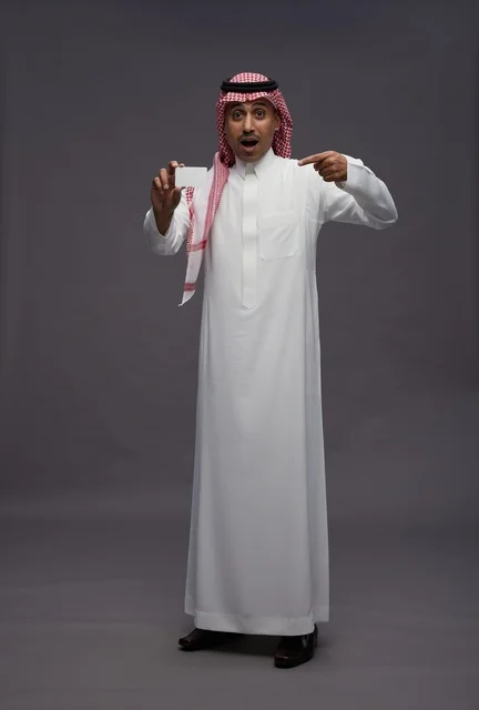 رجل سعودي يحمل بطاقة ائتمان بتعبير مندهش