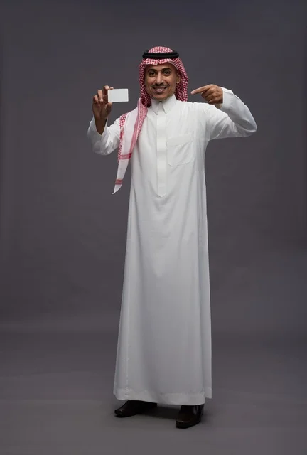 رجل سعودي يحمل بطاقة ائتمان في استوديو خلفية رمادية