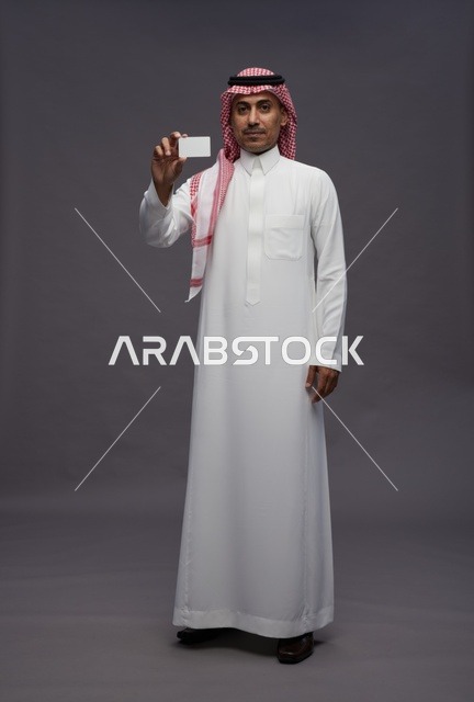رجل سعودي بالزي التقليدي يحمل بطاقة ائتمان