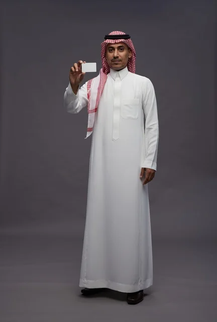 رجل سعودي بالزي التقليدي يحمل بطاقة ائتمان
