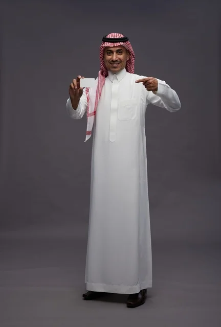 رجل سعودي بالزي التقليدي يحمل بطاقة ائتمانية