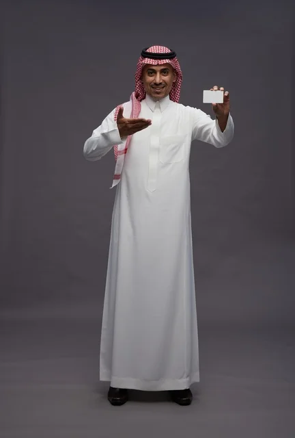 رجل سعودي بالزي التقليدي يحمل بطاقة ائتمان بنكية