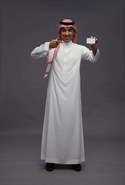 رجل سعودي بالزي التقليدي يحمل بطاقة ائتمان