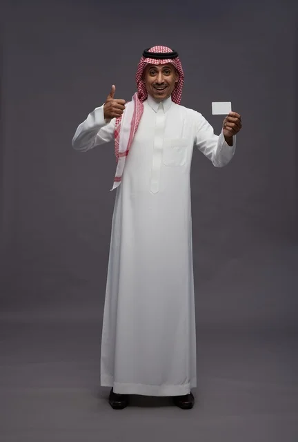 رجل سعودي بالزي التقليدي يحمل بطاقة ائتمان بنكية