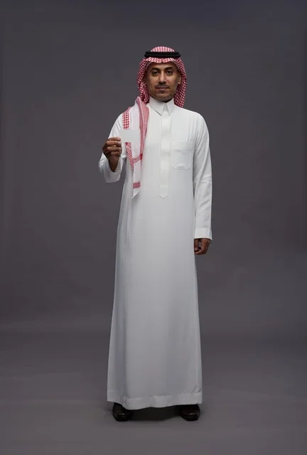رجل سعودي بالزي التقليدي يحمل بطاقة ائتمان