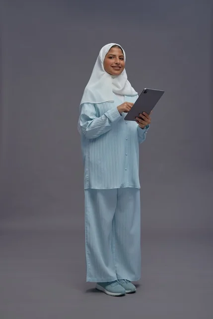 امرأة سعودية بزي كاجوال محتشم تستخدم جهاز لوحي